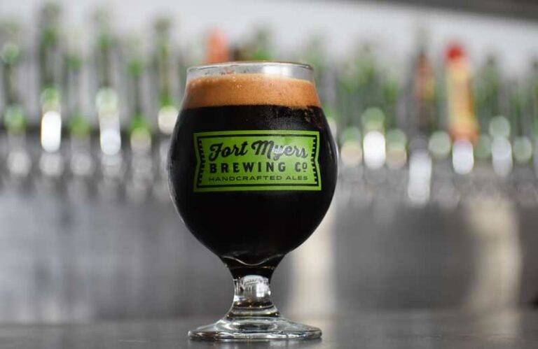 A glass of dark beer sitting on a bar.