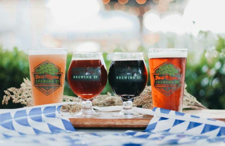 Three glasses of beer on a wooden board.