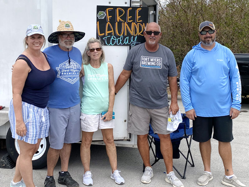 a group of people standing in front of a free laundry truck.